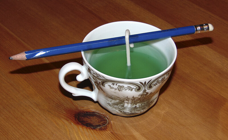 Der Docht wird mit einem Stift am richtigen Platz gehalten solange die Kerze noch flüssig ist.