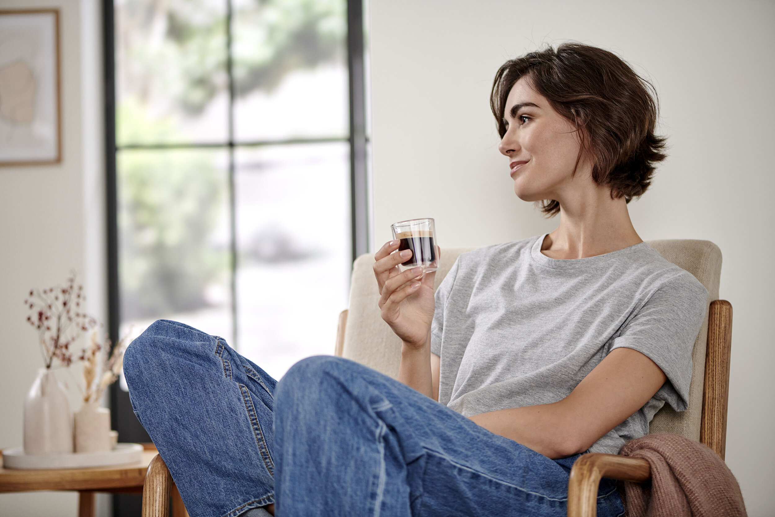 Person entspannt im Sessel mit Espresso in der Hand