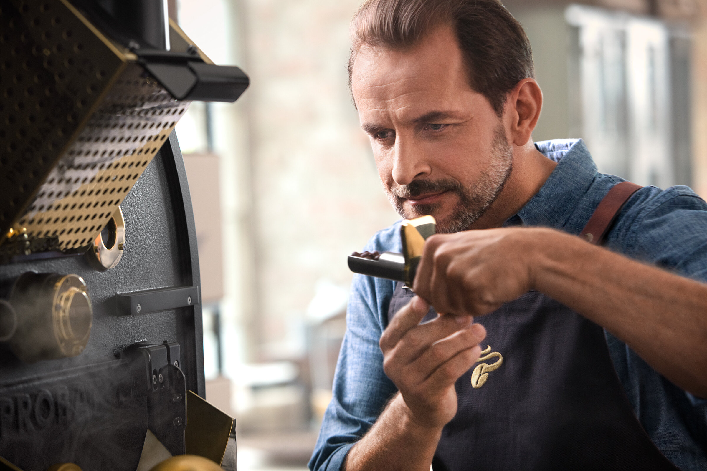 Barista prüft Bohnen an Kaffeeröstmaschine