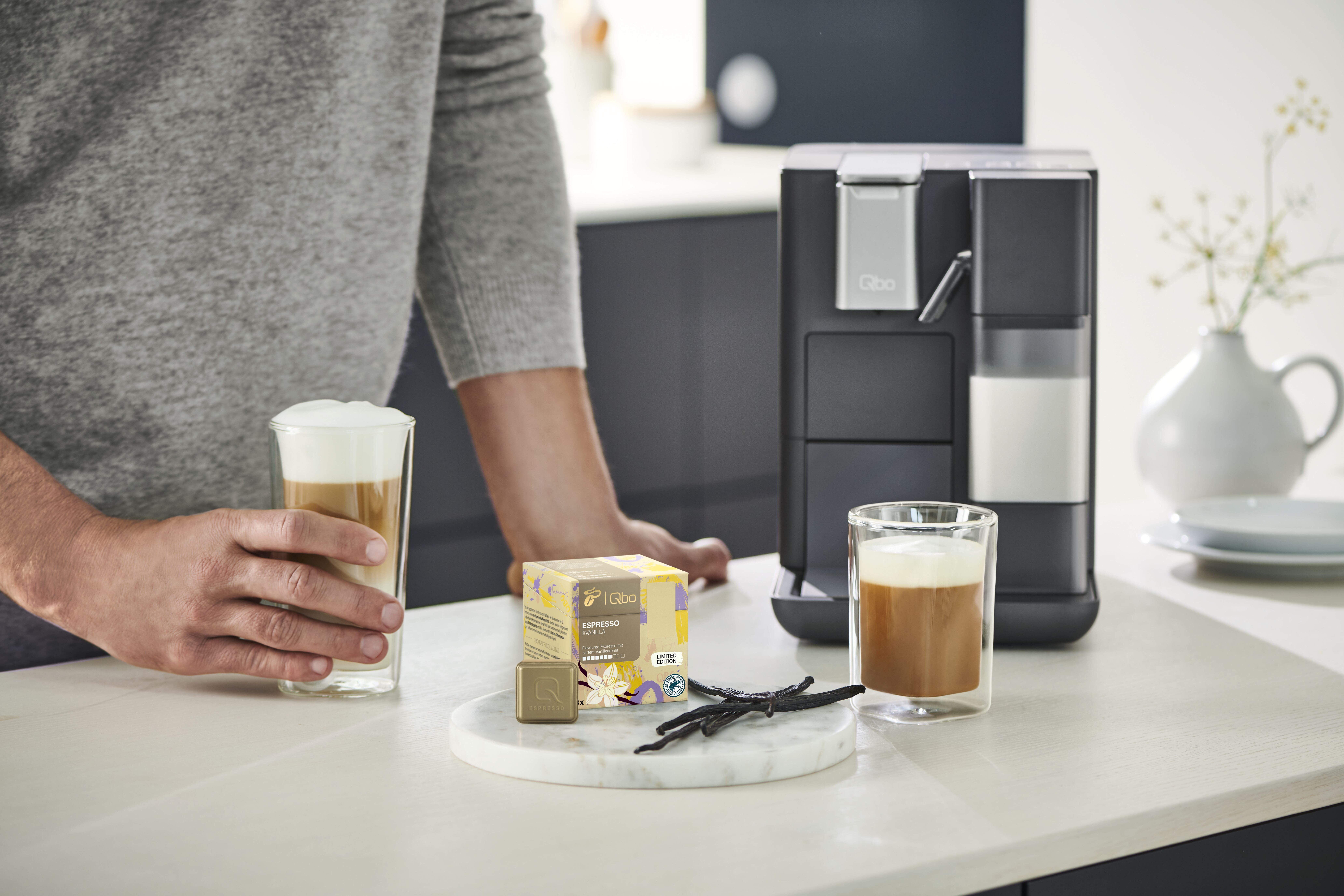 Mann bereitet Latte Macchiato an Kapselmaschine
