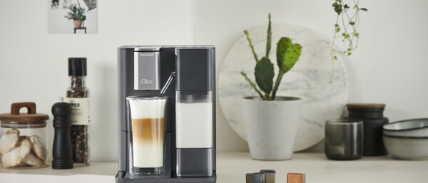 Graue Kaffeemaschine mit Latte Macchiato auf Arbeitsplatte