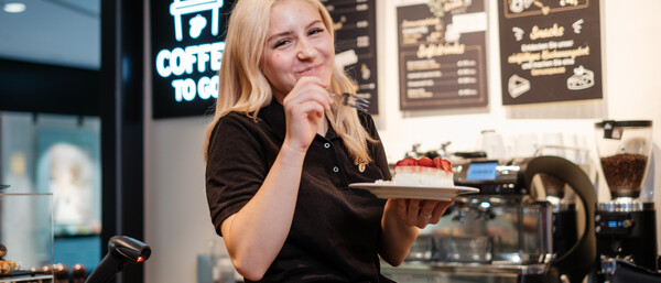 Barista mit Erdbeerkuchen in Kaffeebar
