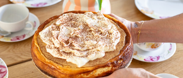 Käsekuchen mit Sahne auf frühlingshaft gedecktem Tisch