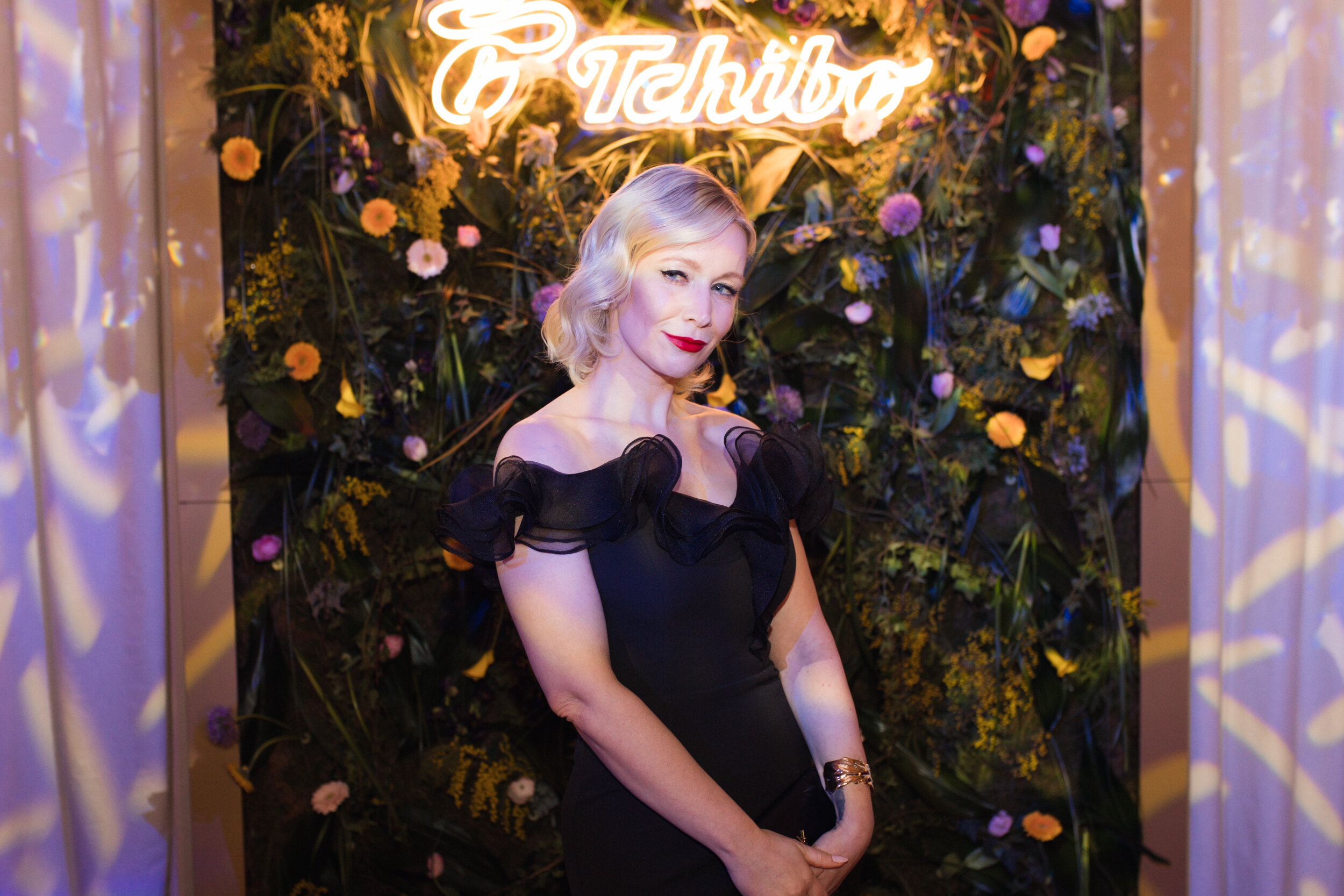Frau im schwarzen Kleid vor Tchibo-Blumenwand