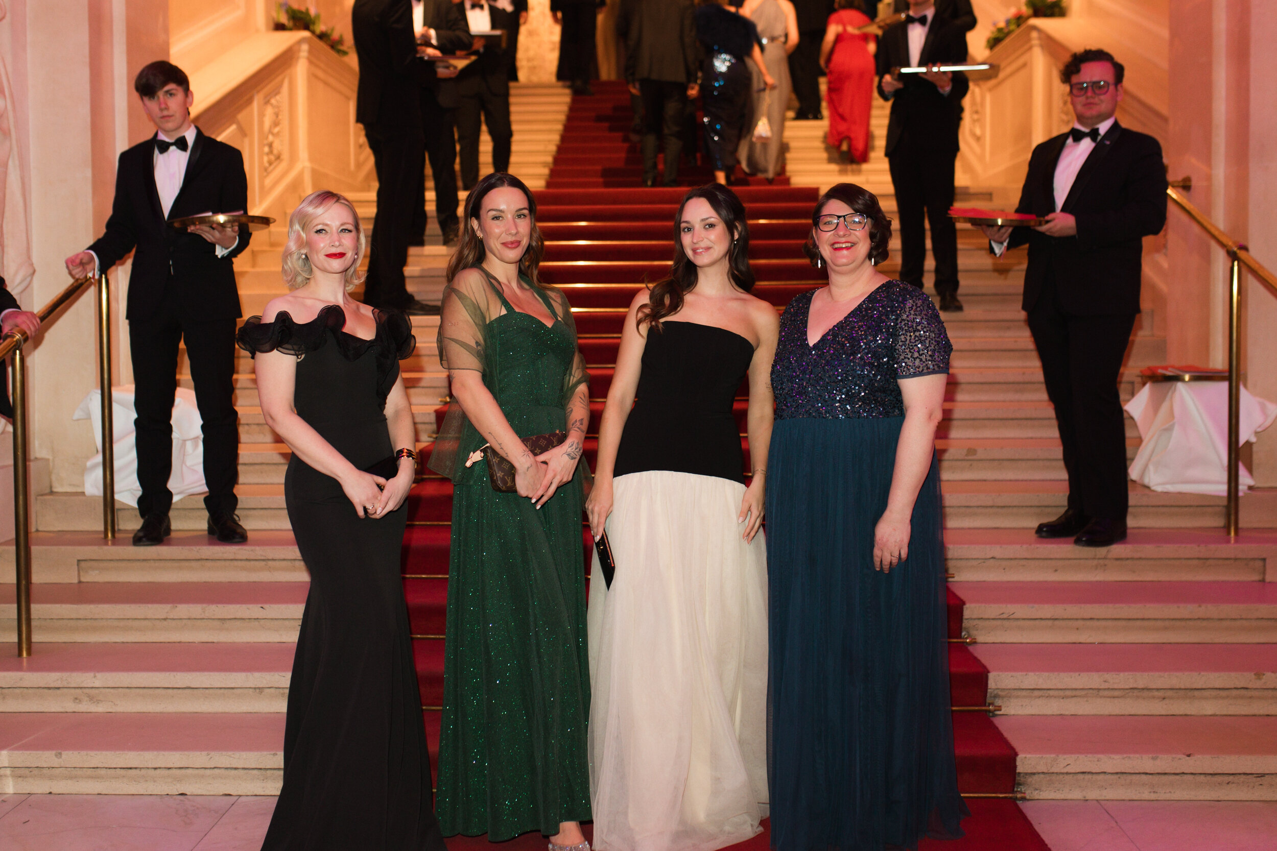 Vier elegant gekleidete Frauen auf rotem Teppich