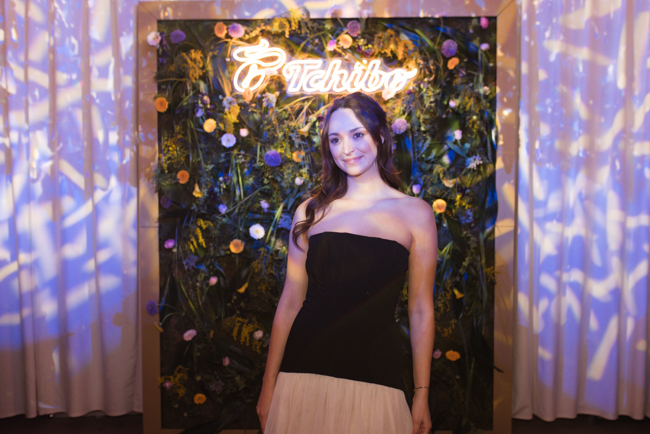 Frau im Abendkleid vor floraler Tchibo-Wand