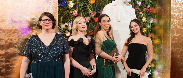 Vier elegant gekleidete Frauen vor Blumenwand