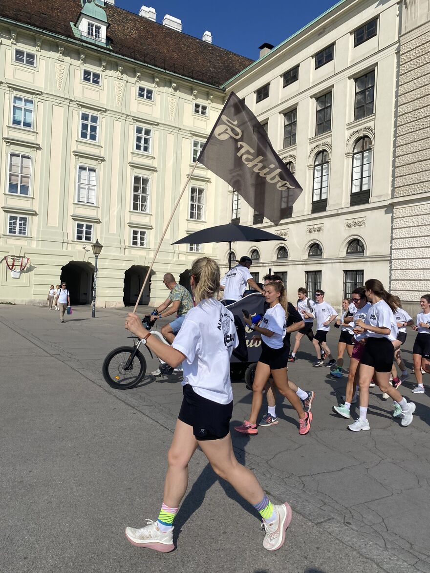 Läufergruppe mit Fahne vor historischem Gebäude