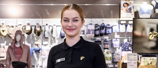 Verkäuferin im Bekleidungsgeschäft vor Regalen