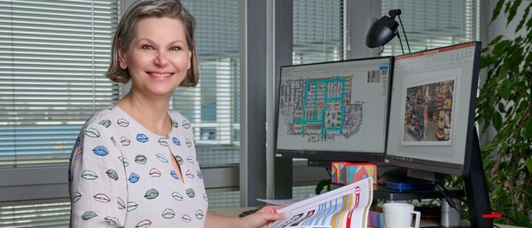 Person im Büro vor zwei Monitoren mit Plänen