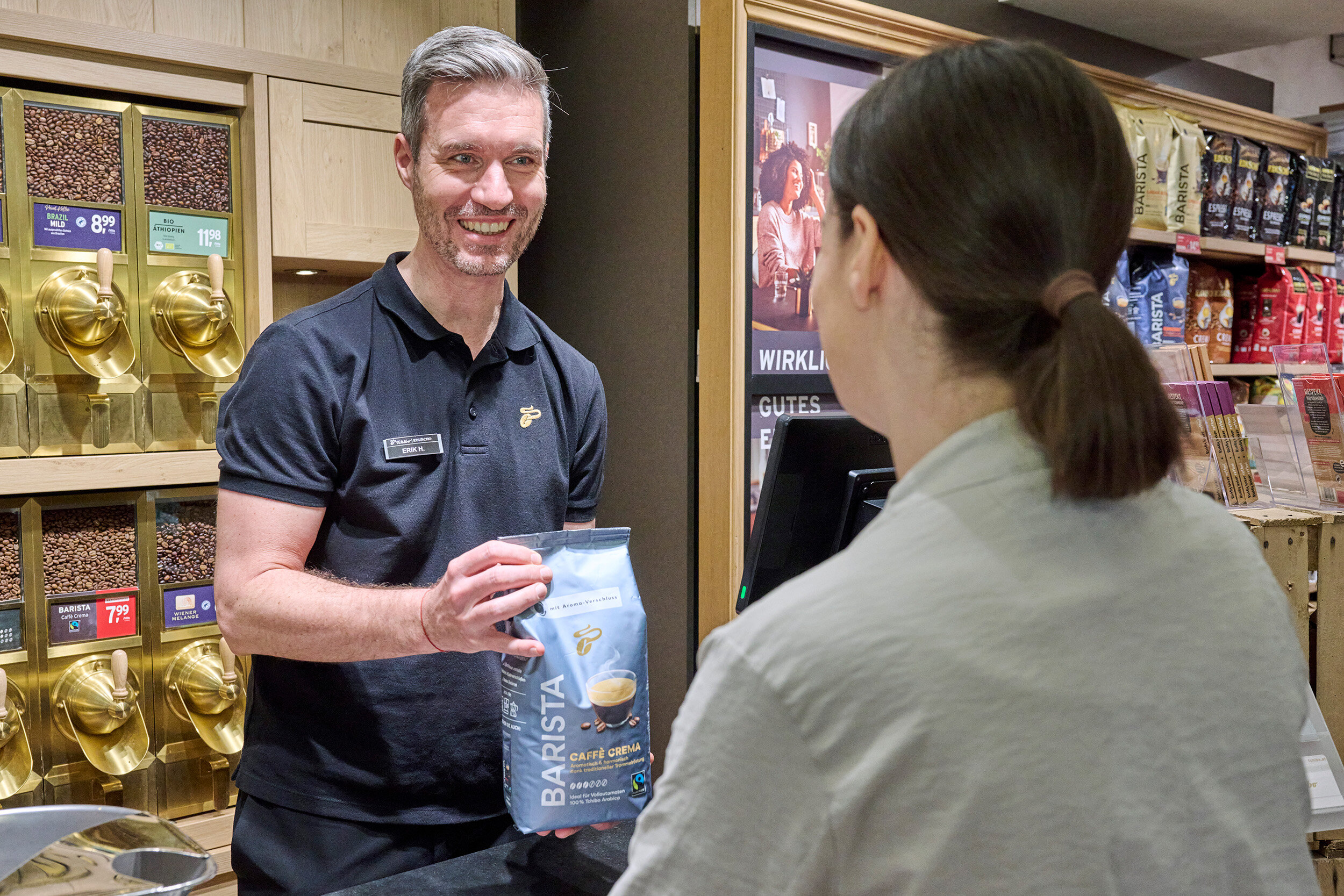 Verkäufer überreicht Kundin eine Kaffeepackung