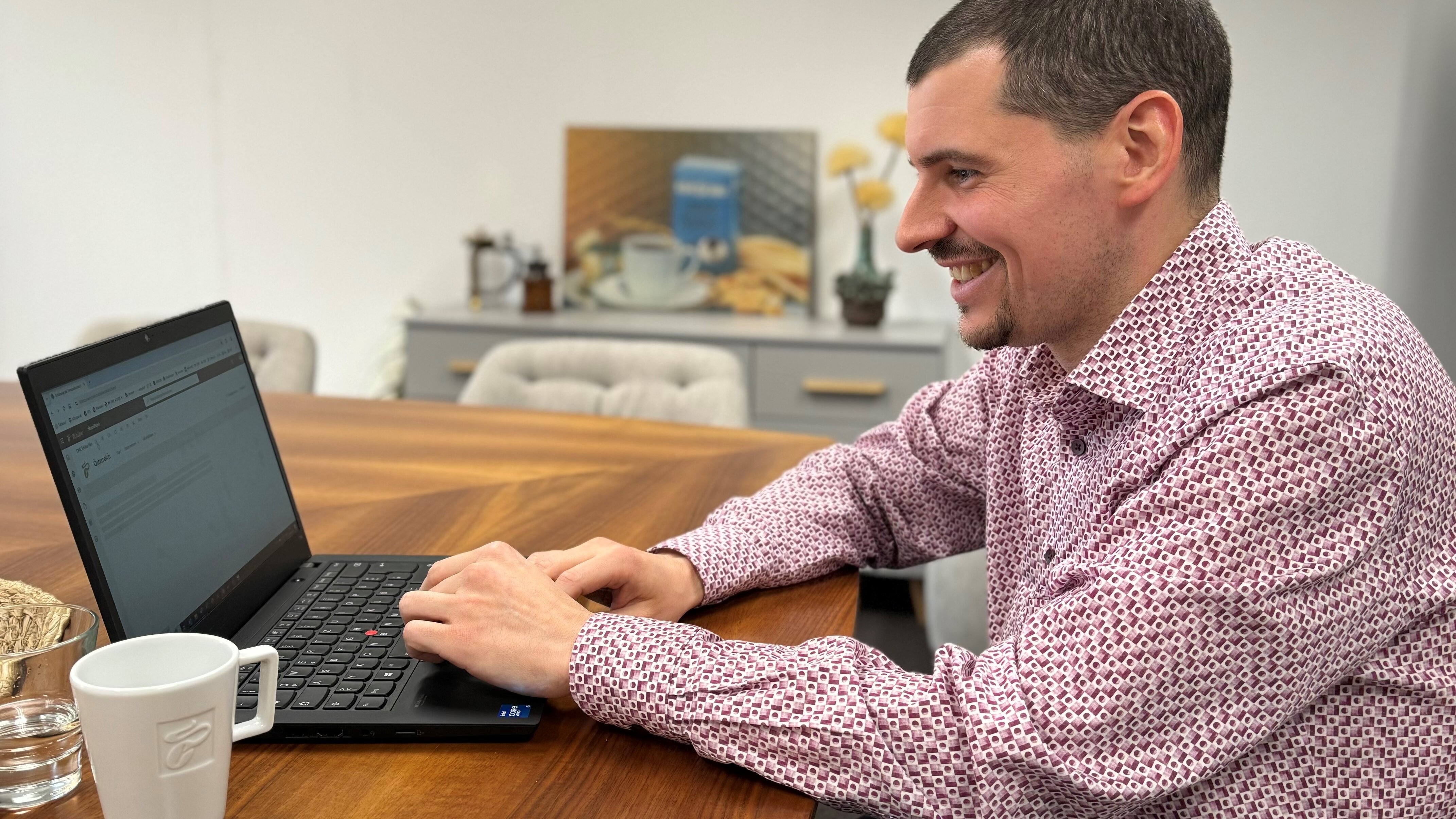 Person arbeitet am Laptop an Holztisch