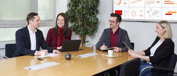 Vier Personen im Meeting mit Präsentation auf Monitor