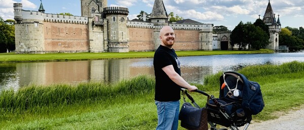 Person mit Kinderwagen vor Schloss und Wassergraben