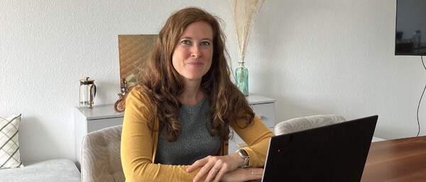 Frau arbeitet am Laptop an Holztisch