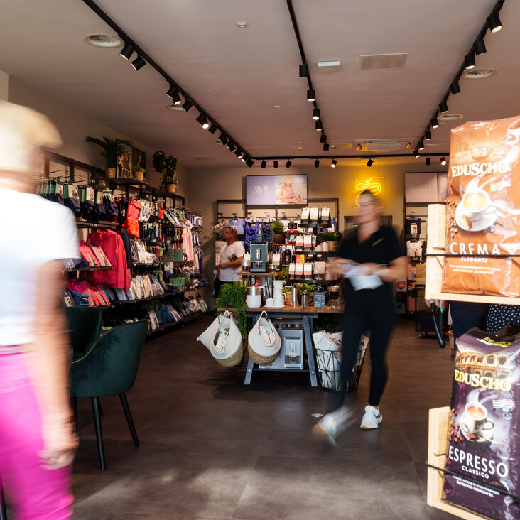 Belebter Laden mit Kaffee- und Textilregalen