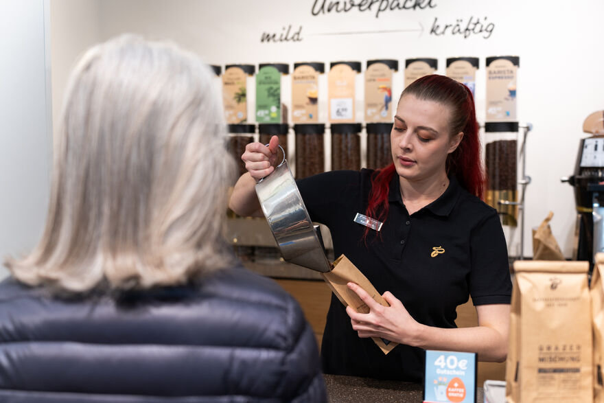 Barista füllt Kaffeebohnen in Papiertüte für Kundin