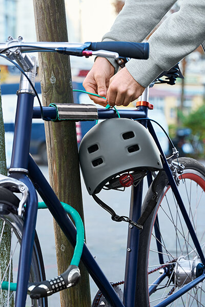 Person schließt Fahrrad mit Helm an Pfahl an