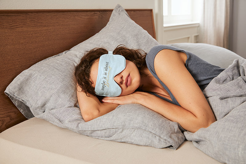 Frau schläft mit blauer Schlafmaske im Bett