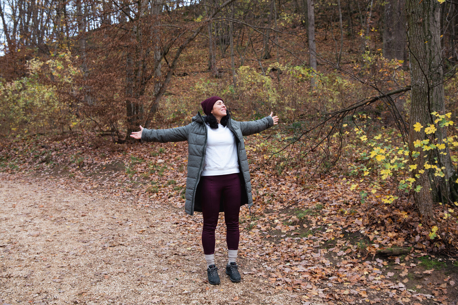 Person mit ausgebreiteten Armen im herbstlichen Wald