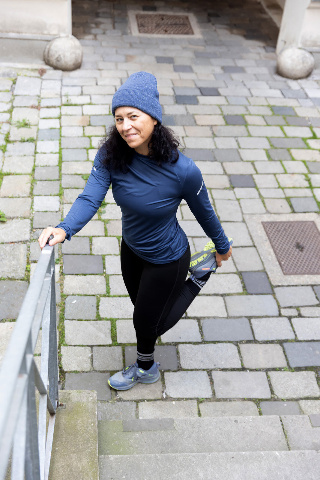 Joggerin dehnt Bein an Treppengeländer draußen