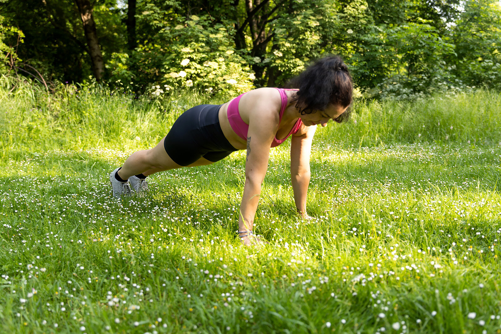 Frau macht Plank auf Wiese im Park