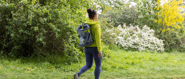 Frau mit Rucksack wandert auf Pfad im grünen Park