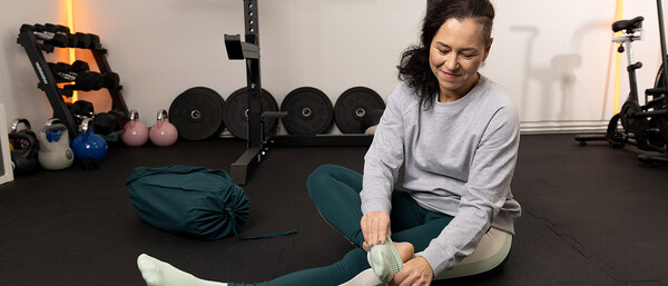 Frau zieht im Fitnessraum Sportsocken an