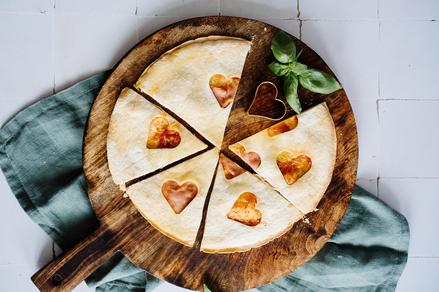 Herzförmig verzierte Pizza auf Holzbrett