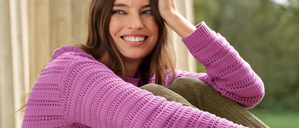 Person im pinken Strickpullover sitzt nachdenklich