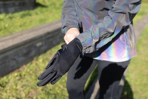 Link: Großansicht des Bildes - Bildinhalt: Person zieht schwarze Handschuhe im Freien an