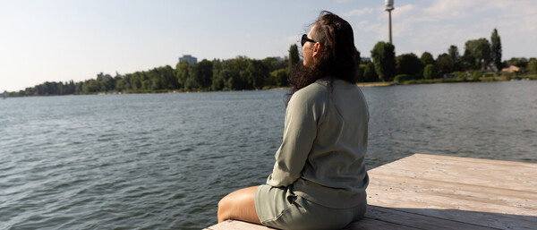 Person sitzt auf Holzsteg am See