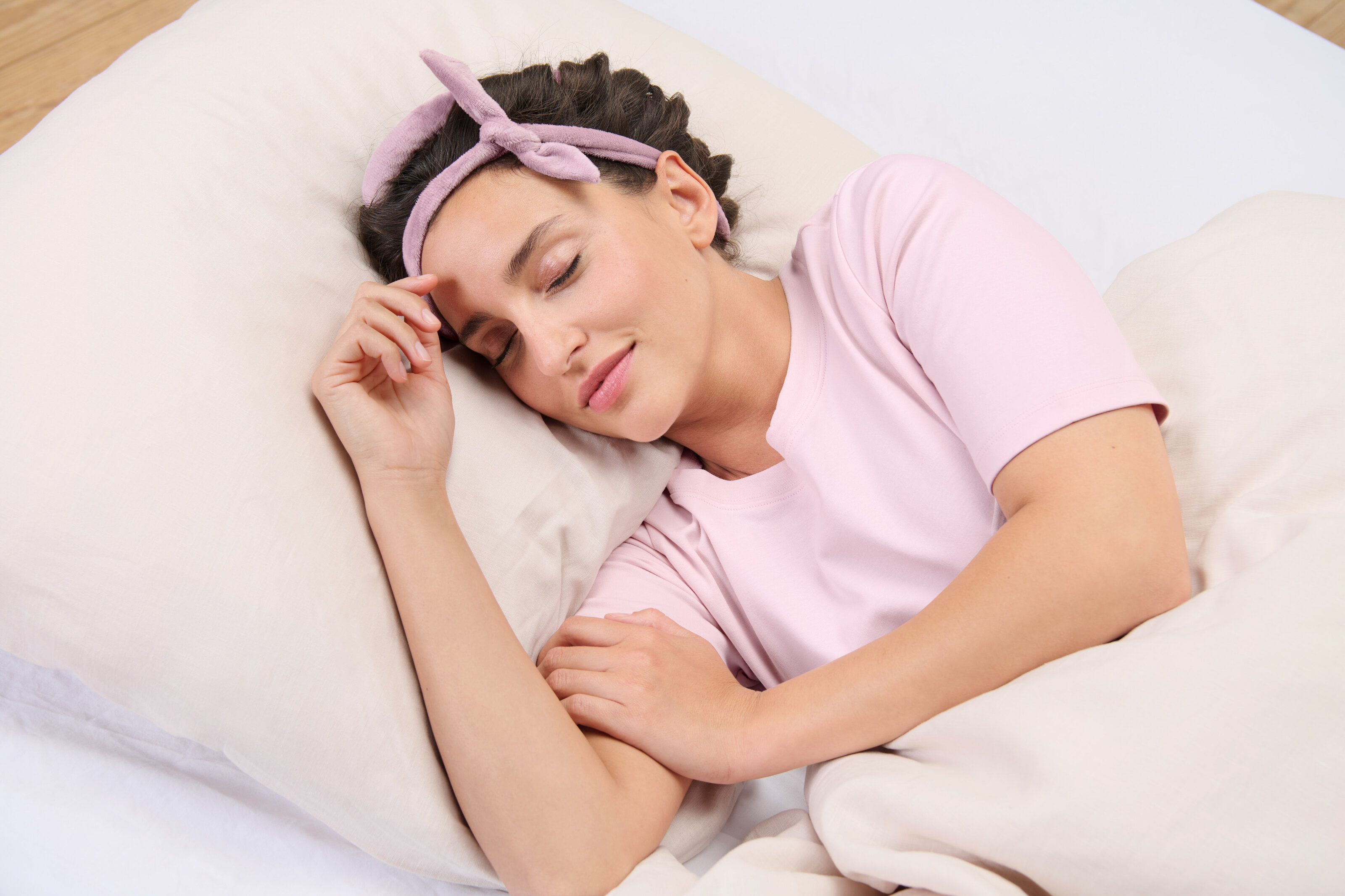 Person schläft seitlich im Bett mit rosa Stirnband