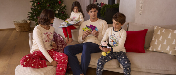 Familie im Weihnachts-Pyjama vor Tannenbaum
