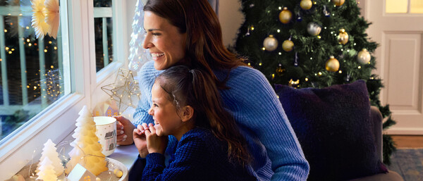 Mutter und Kind schauen an Weihnachten aus dem Fenster