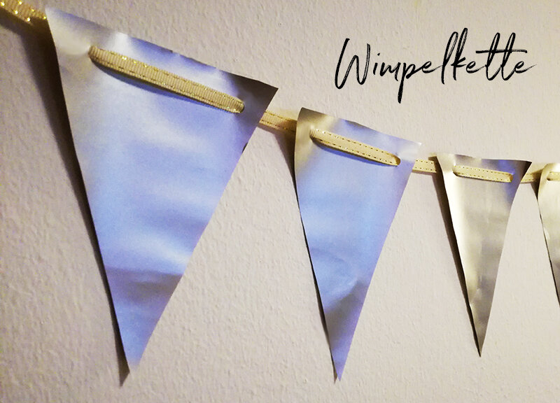 Blau-goldene Wimpelkette an heller Wand