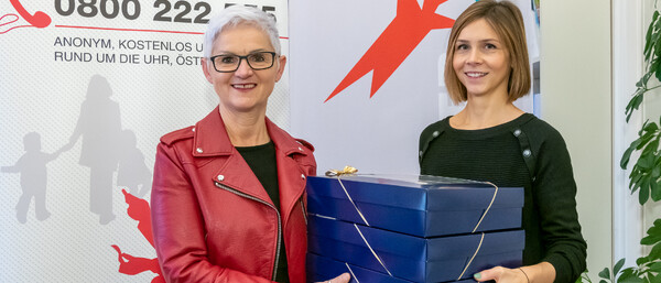 Zwei Frauen halten gestapelte Geschenkschachteln