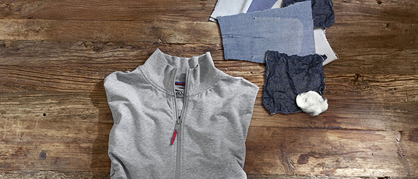 Grauer Pullover mit Stoffmustern auf Holztisch