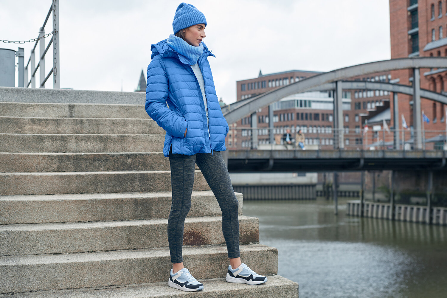 Person in blauer Winterkleidung auf Treppe am Kanal