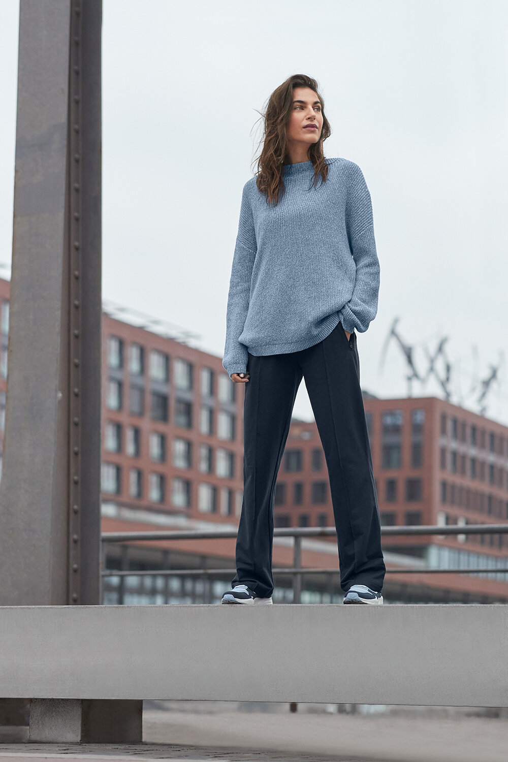 Person in blauem Pullover steht urban erhöht