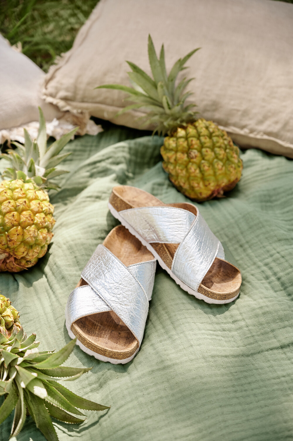 Silberne Sandalen auf Decke mit Ananas