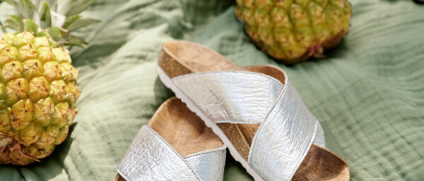 Silberne Sandalen auf Decke mit Ananas