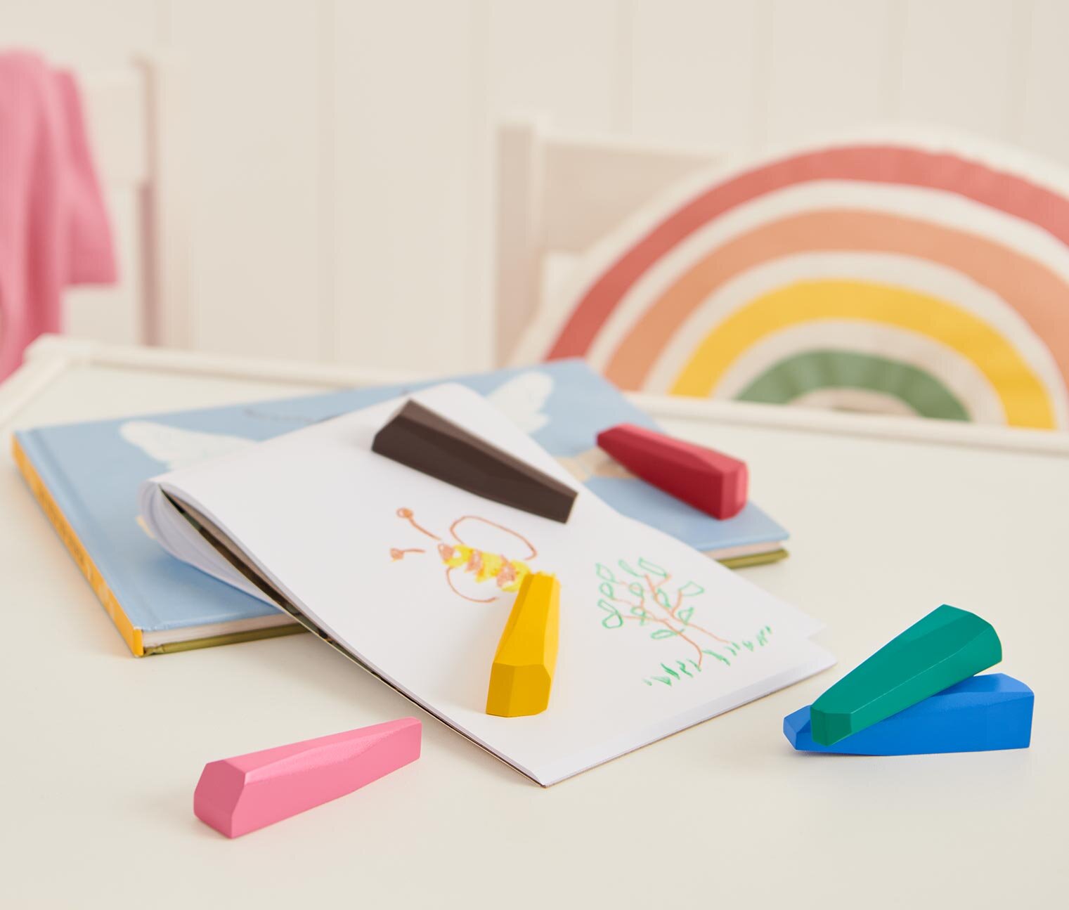 Kinderzeichnung mit bunten Wachsmalstiften auf Tisch