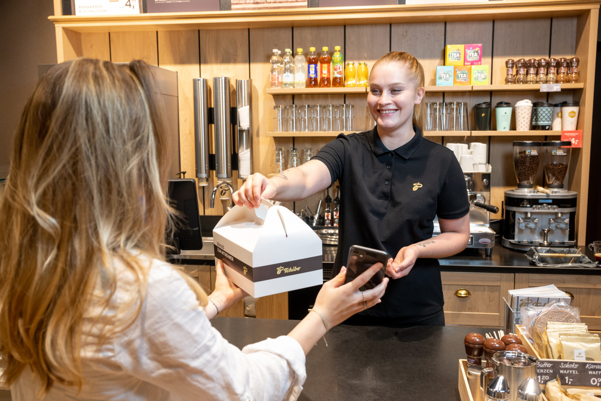 Kundin erhält Gebäckbox an Café-Theke