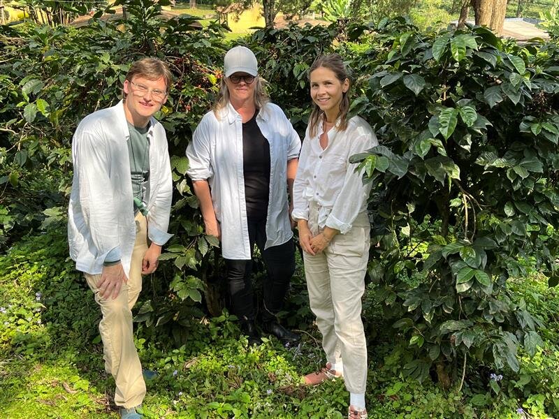 Drei Personen in heller Kleidung im dichten Garten