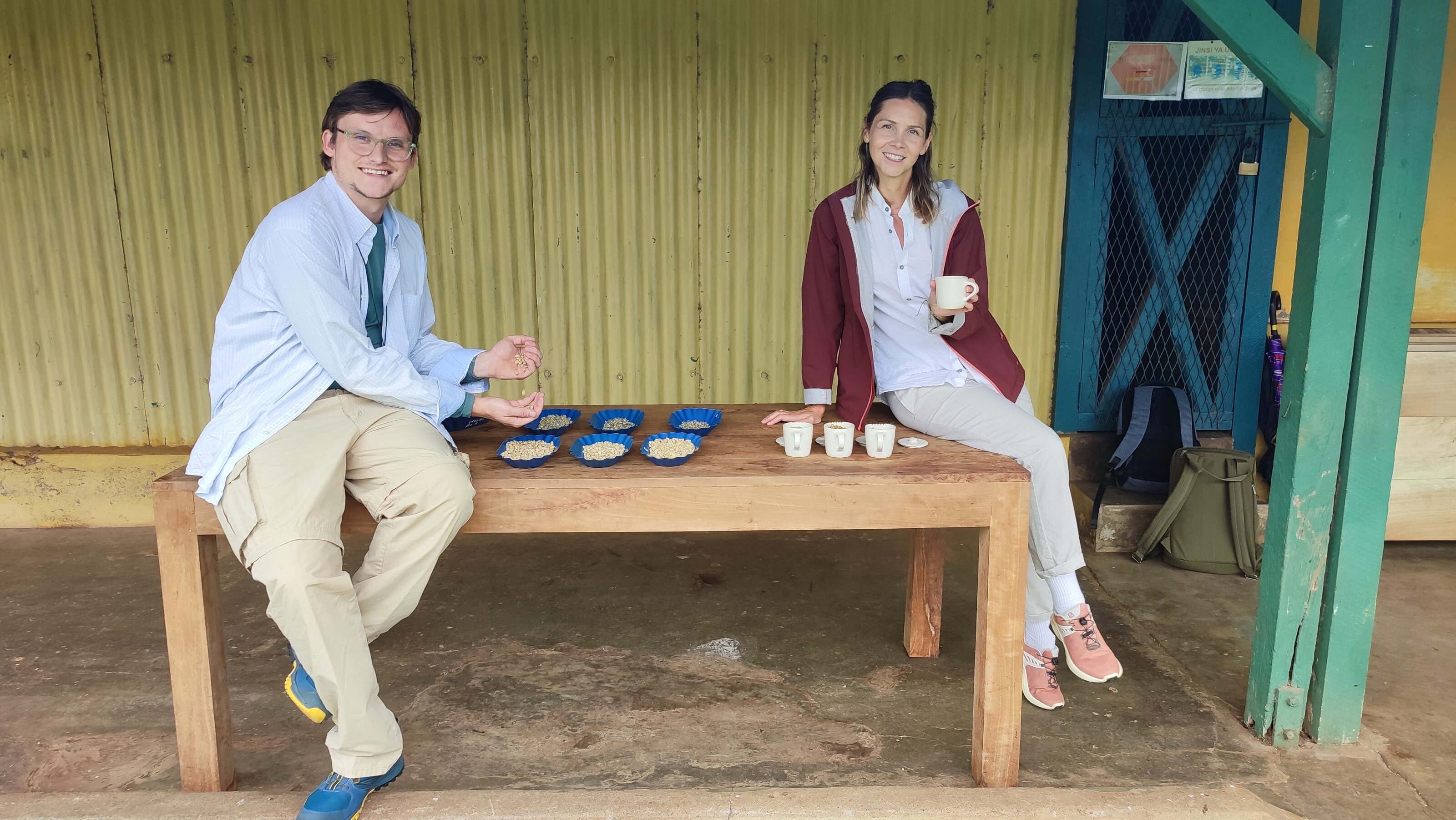 Zwei Personen probieren Kaffeebohnen am Holztisch