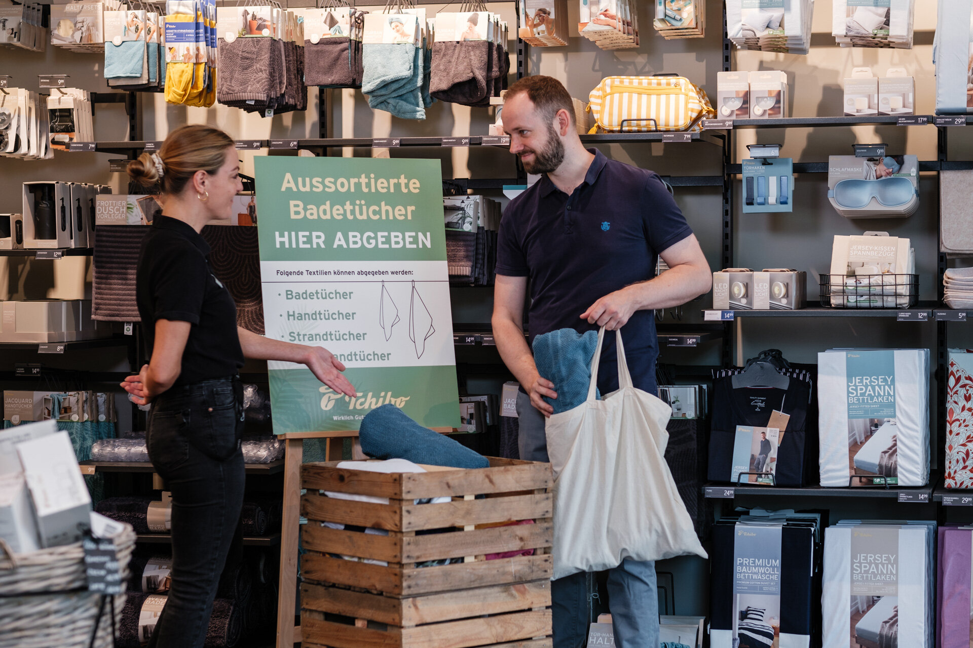 Zwei Personen geben Handtücher in Sammelbox im Laden