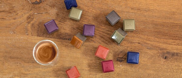 Espressotasse und bunte Kaffeekapseln auf Holz