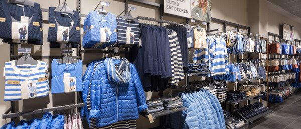 Kleidungsgang mit blauen Jacken und Streifenshirts