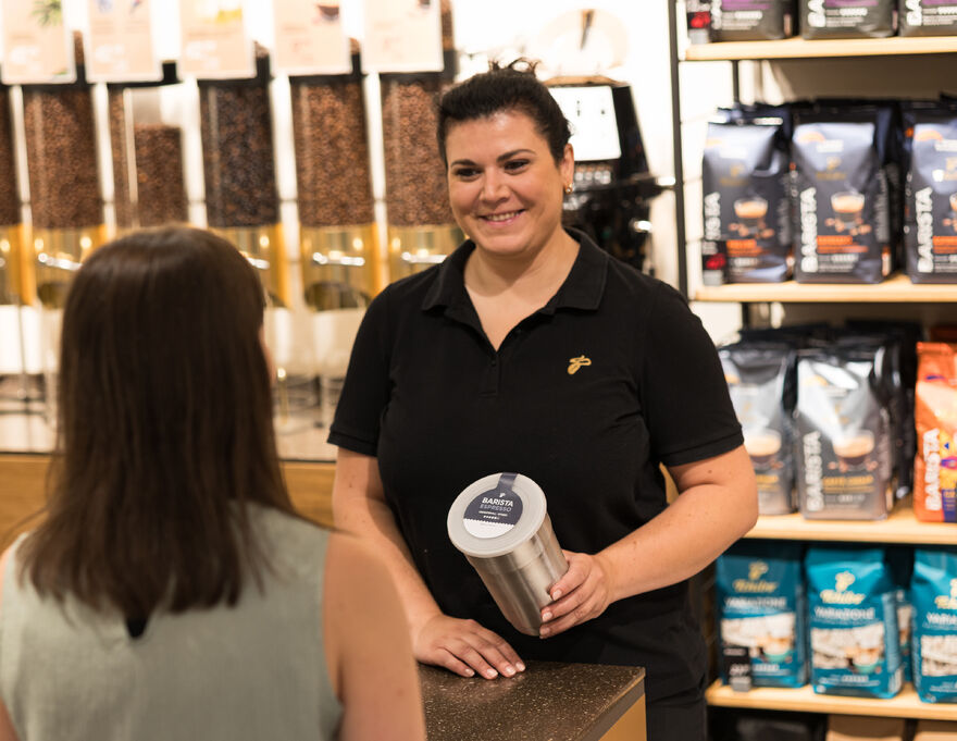Verkäuferin überreicht Kundin eine Kaffeebüchse